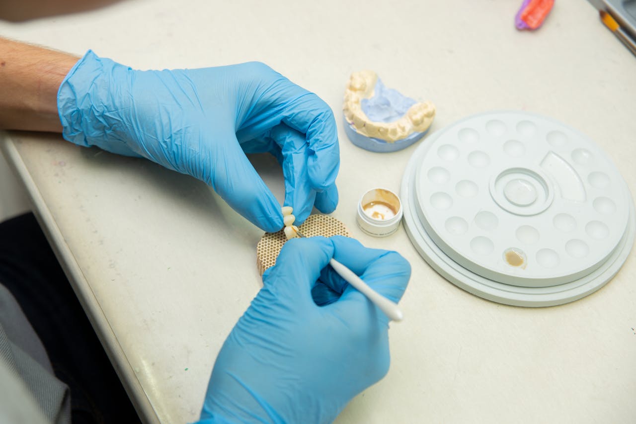 Dental technician using tools to craft a tooth implant in a lab setting.